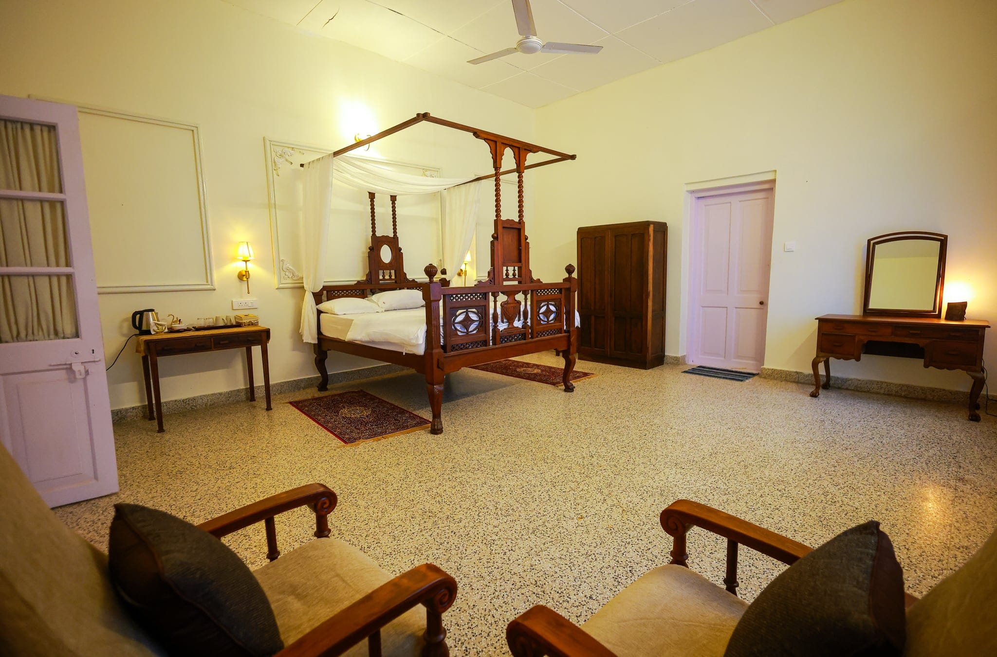 Four-poster bedroom with a red-oxide floor at Heyday Planter's Portico, near Thenmala, Kollam, Kerala